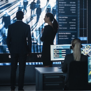 Investigation teams using digital intelligence solutions stand in front of a computer screen.