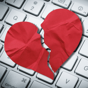 A broken heart on top of a computer keyboard.